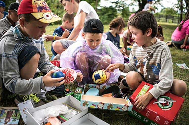Three campers show off their shoebox gifts to one another in Zarichia.