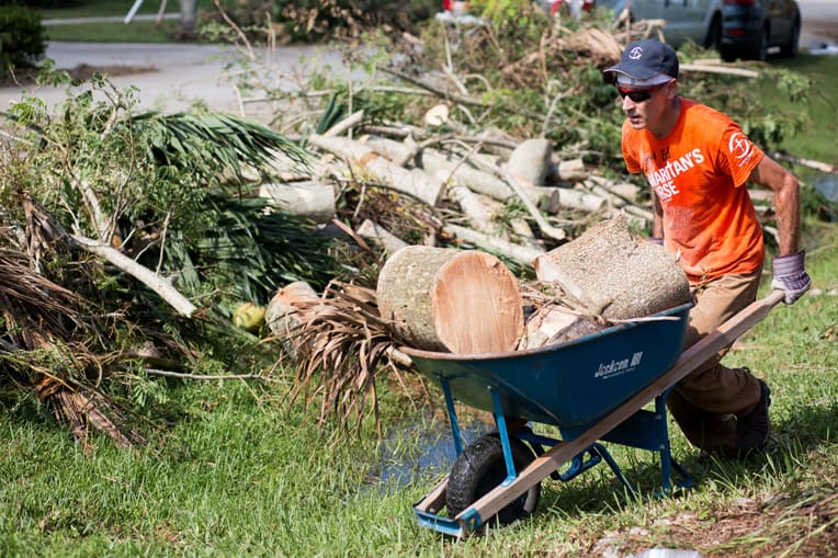 A Samaritan's Purse volunteer works hard clearing trees and debris in Marta's yard.