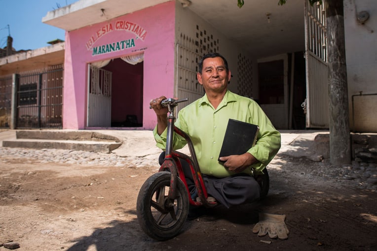 Pastor José Benítez uses a work glove to protect his hand while pushing his scooter down the roads of his hometown in northwest Mexico. He takes the Gospel to remote mountain villages through Operation Christmas Child.