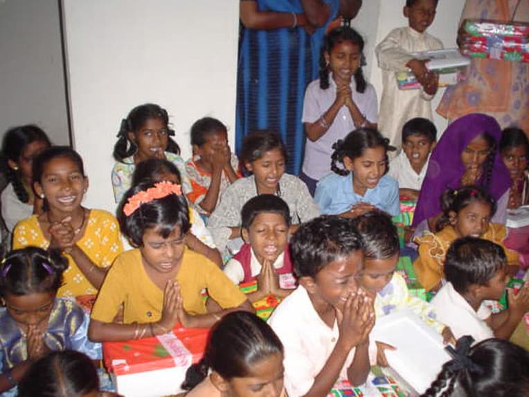 Children in South Asia pray before opening the shoeboxes Raja and Ramya delivered to them from Christians around the world.