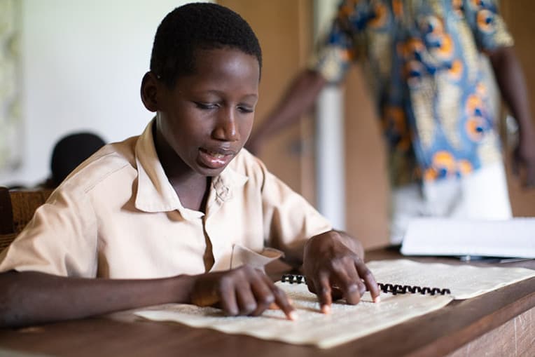Annani reads from his braille textbook during morning classes at The Village of Light School for the Blind.