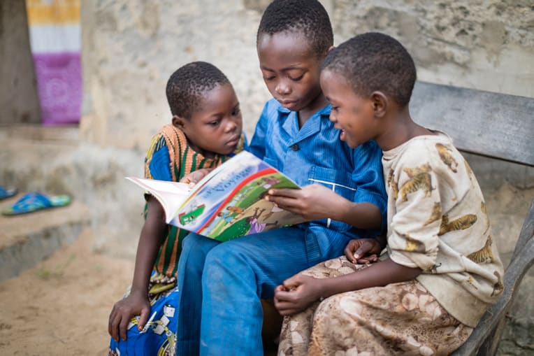 Kevin reads to siblings from The Greatest Journey booklet. The curriculum has helped introduce his family to God's Word.
