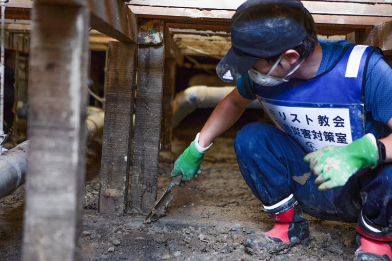 Volunteers are helping to clear mud from floor beams in a flood-stricken town in southern Japan.