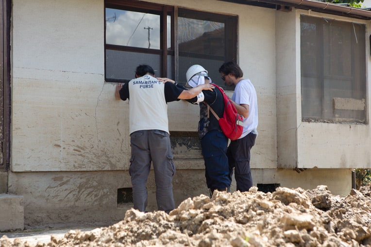 Members of our disaster response team pray with a worker helping clean up flooded homes in southern Japan.