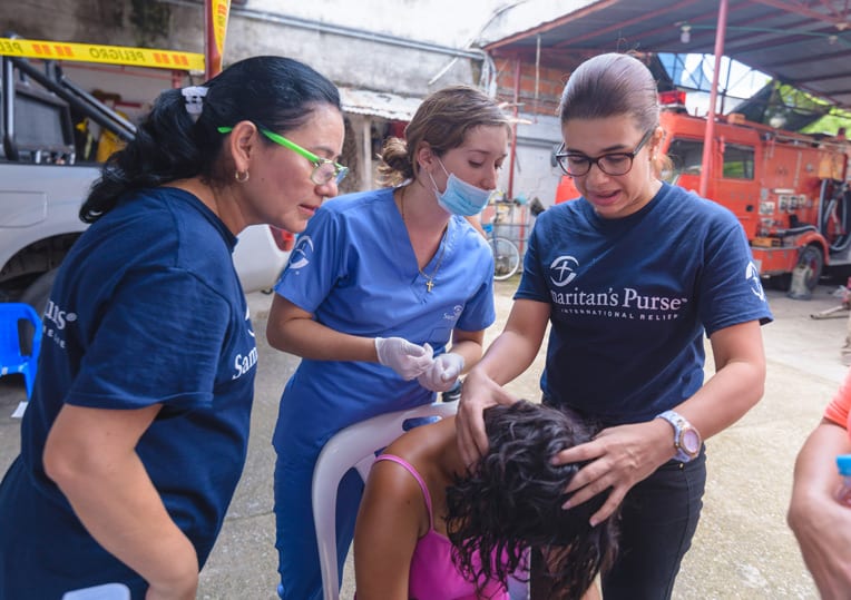 Doctor Maria Del Los Angeles Sarmiento (right) and two nurses assess a woman's wounded head.