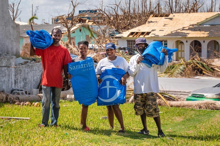 Gerald (far left) and Rosie (second from right) stand with their neighbors after receiving shelter plastic from Samaritan's Purse.