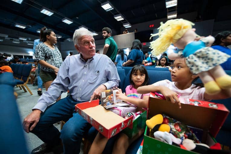 Franklin Graham watches as a young girl discovers a special doll in her shoebox.