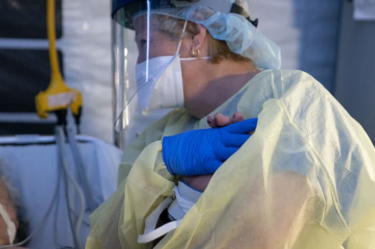 Claudia, a night shift ICU nurse, holds Umberto's hand during his time on a ventilator.