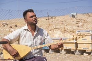A Yazidi serenades the bees he received from Samaritan’s Purse.