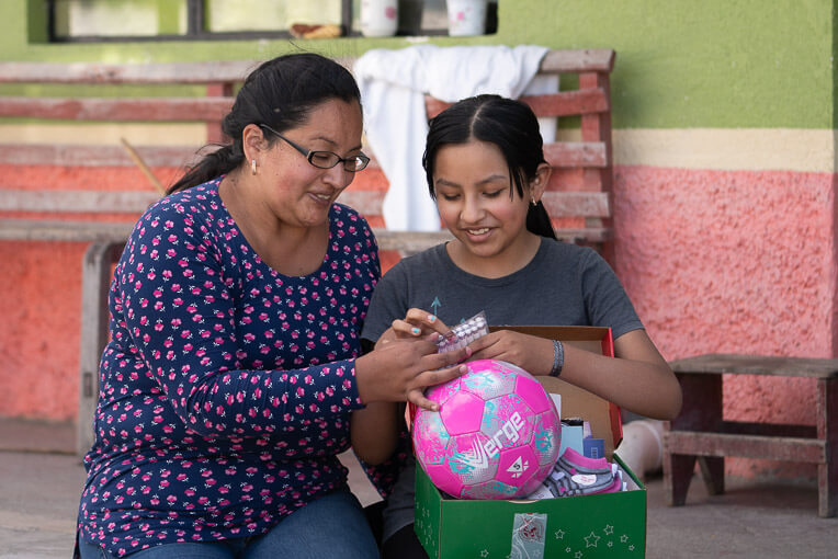 Romina shows her mother the items she received in her shoebox gift.