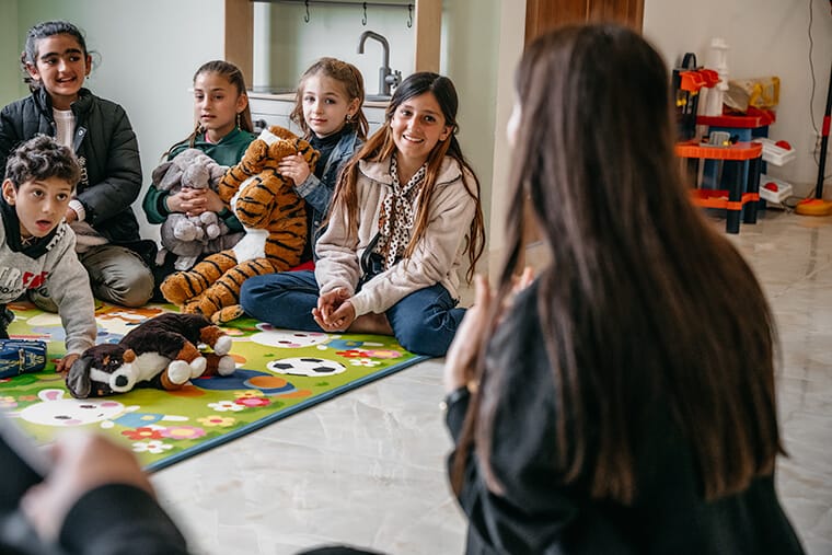 Sheren (second from right) delights in hearing a Bible story at the child friendly space.