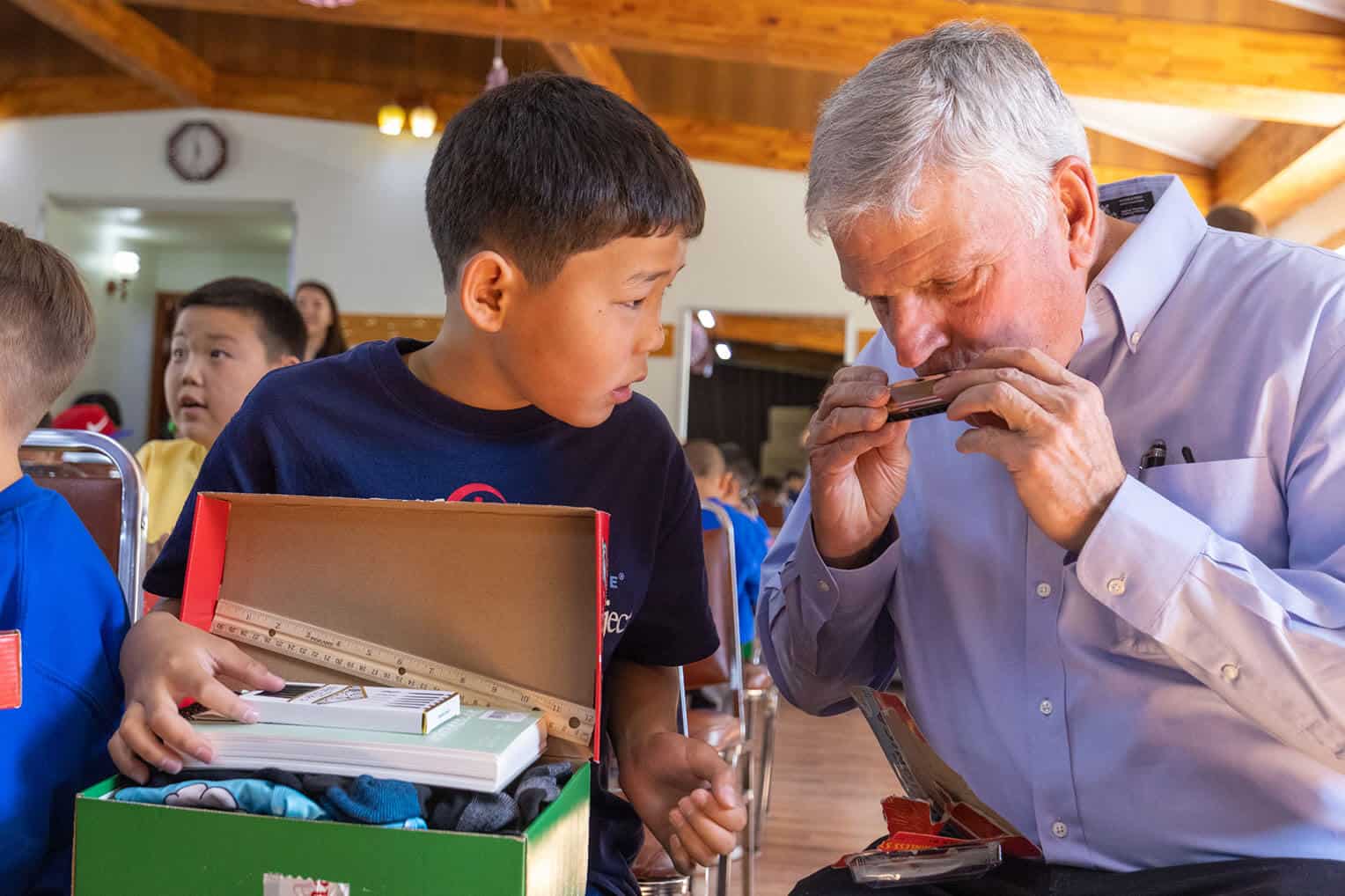 Franklin Graham shows Erdembayar how to play a harmonica, one of the gifts he received in his shoebox.