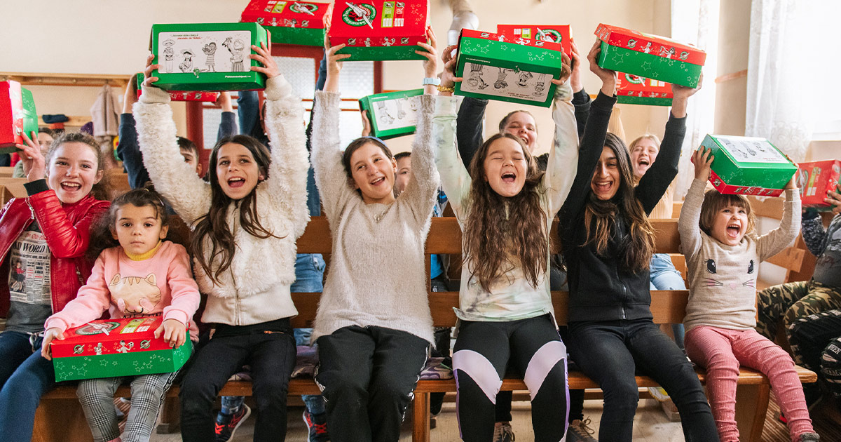 Children joyfully open Operation Christmas Child shoebox gifts during an outreach event with their local church.