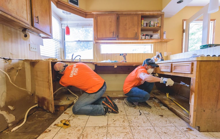 Volunteers rip out waterlogged cabinets in the Sherman's home.