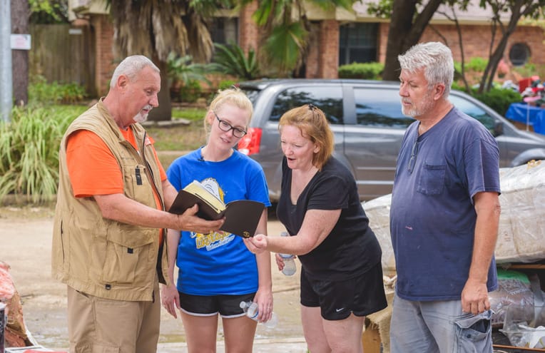 Paige and her parents receive a Bible signed by the volunteers who worked on their home.