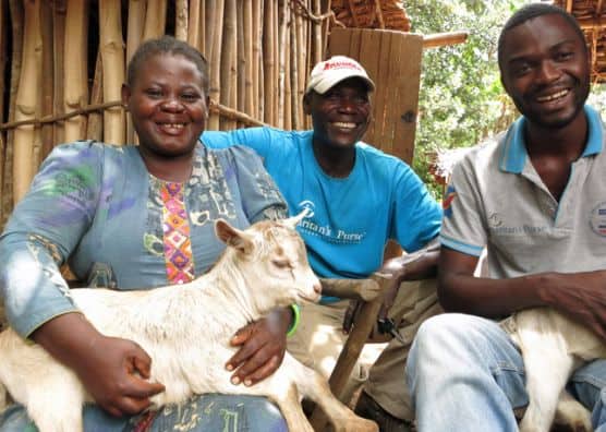 Mwapili holds goat beside two Samaritan's Purse staff