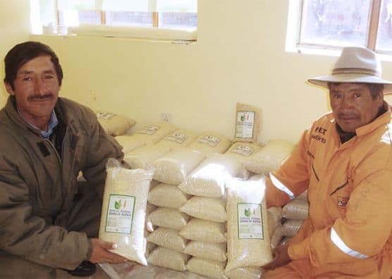 Rene and another man each hold a bag of grain