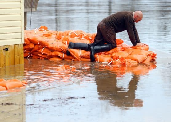 Man placing sandbags to ward off floodwaters from home