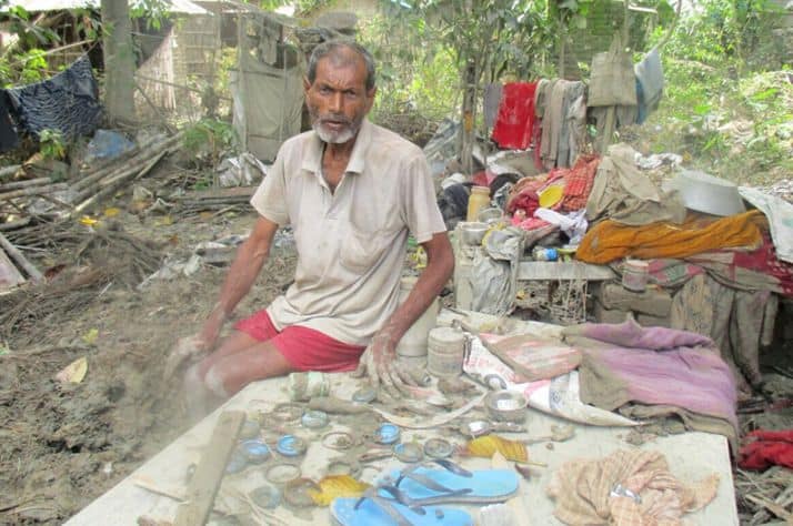 A Nepali man sorts through his few belongings that remain after devastating floods.