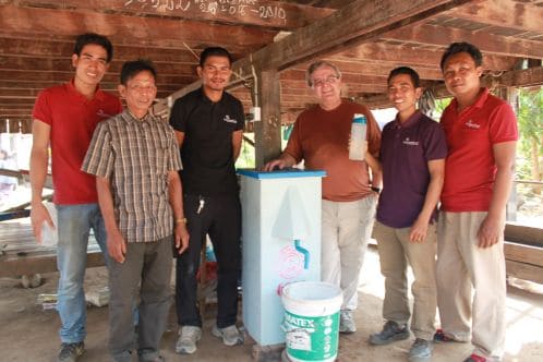 Dr. David Manz (brown shirt) and Samaritan’s Purse staff visit with the proud owner (plaid shirt) of this BioSand Water Filter and test the filter’s flow as part of regular monitoring procedures. The owner says he loves his filter because it keeps him healthy. 