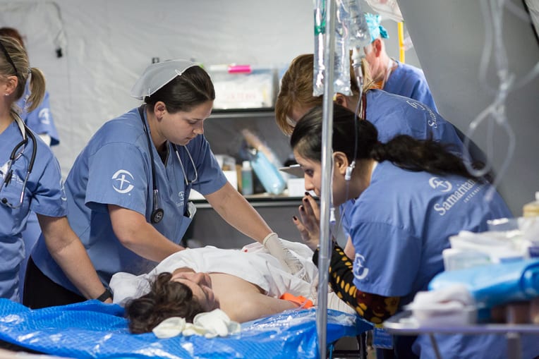 Field hospital staff assess a patient's injuries.