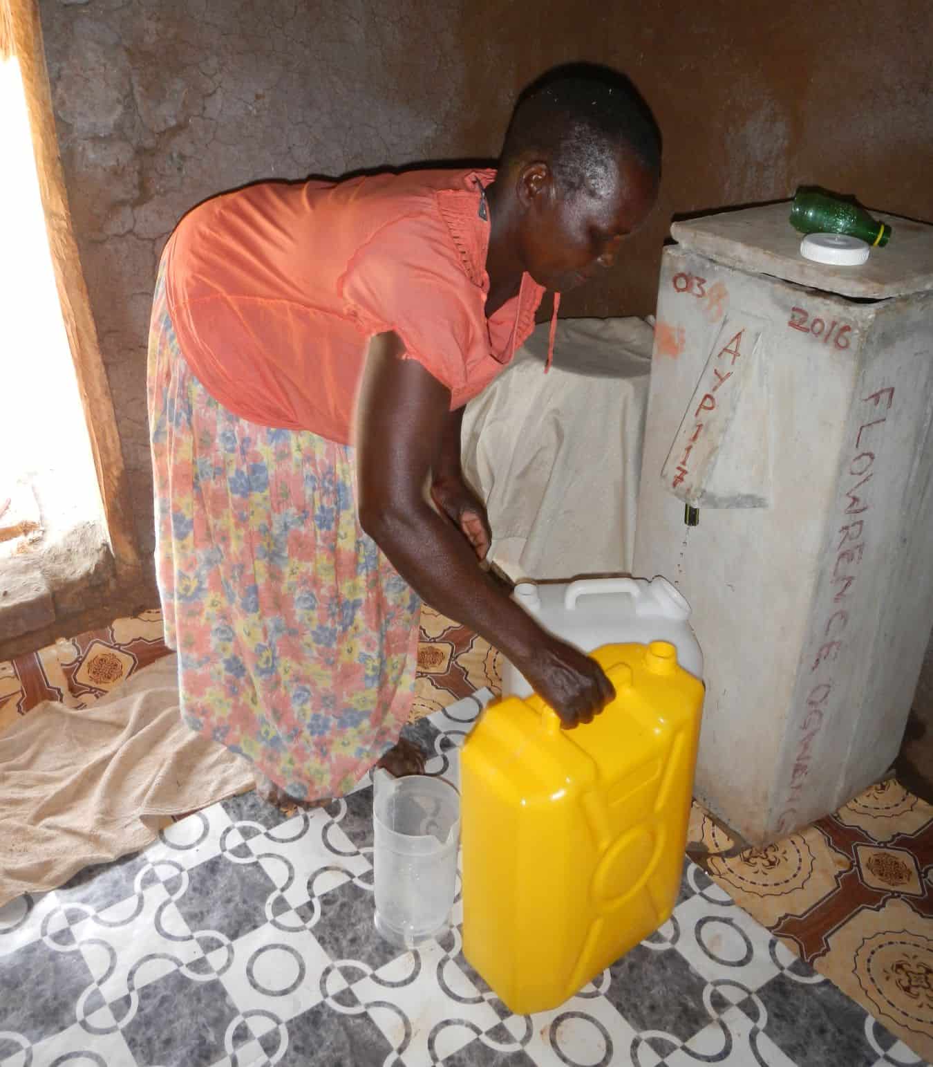Florence Akullo gathering filtered water from her BioSand Water Filter.