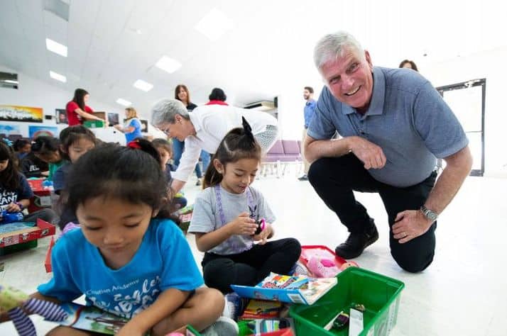 Samaritan's Purse President Franklin Graham joins children opening their gifts.
