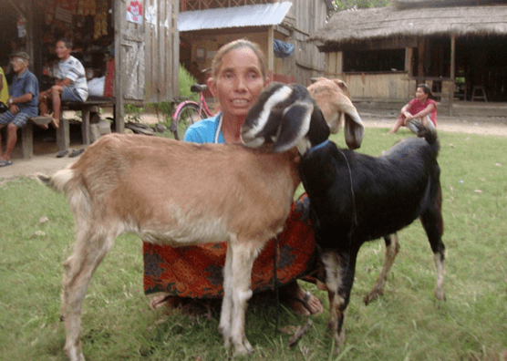 Woman crouches next to goats given to her by Samaritan's Purse.
