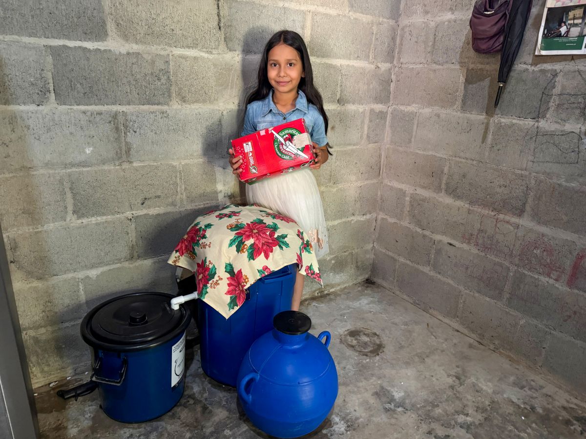 EXPRESSIONS OF GOD’S LOVE: Dayana stands with herOperation Christmas Child shoebox gift and her familiy’s BioSand Water Filter provided by Samaritan’s Purse and friends like you.