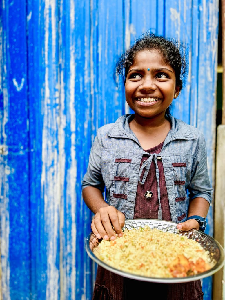 Avani, a young girl from Sri Lanka, with a bowl of food.