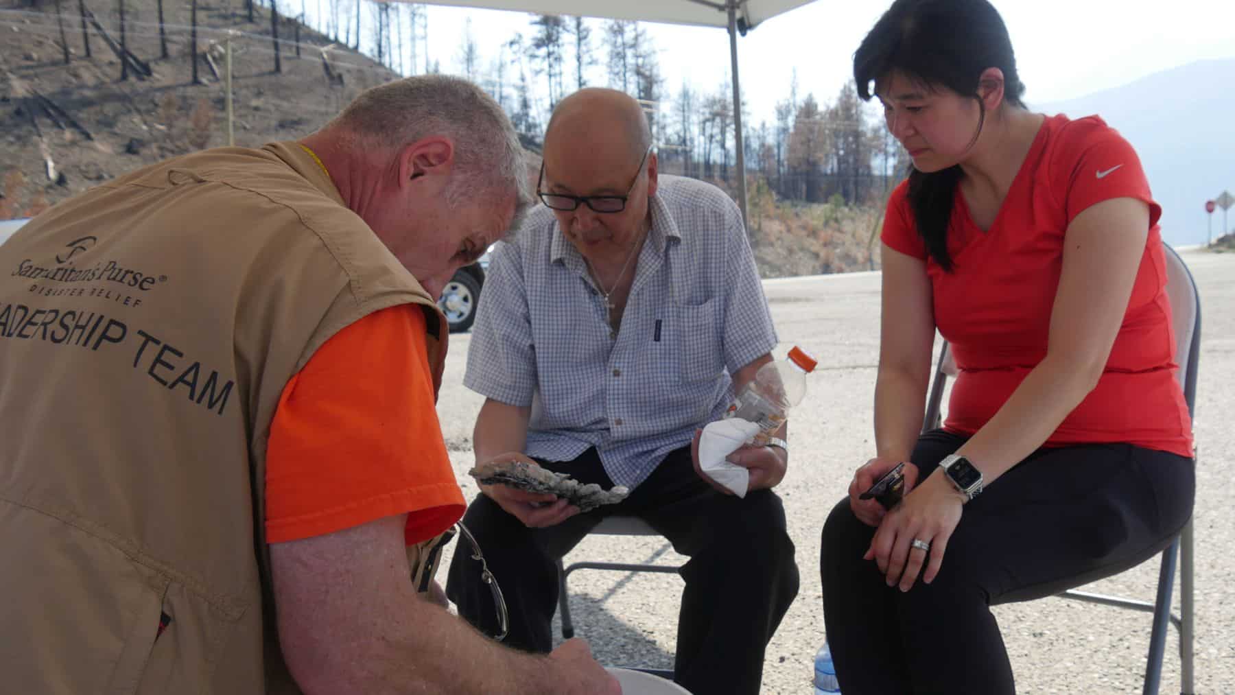 Kenny and his daughter, Margaret, meet with a Samaritan’s Purse site leadership team member to look at some of the items recovered from the ashes.