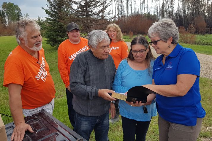 Samaritan’s Purse volunteers watch while Paddle Prairie Metis Settlement residents Wilson and Jessie Gaucher receive a Bible from a Billy Graham Rapid Response Team chaplain.