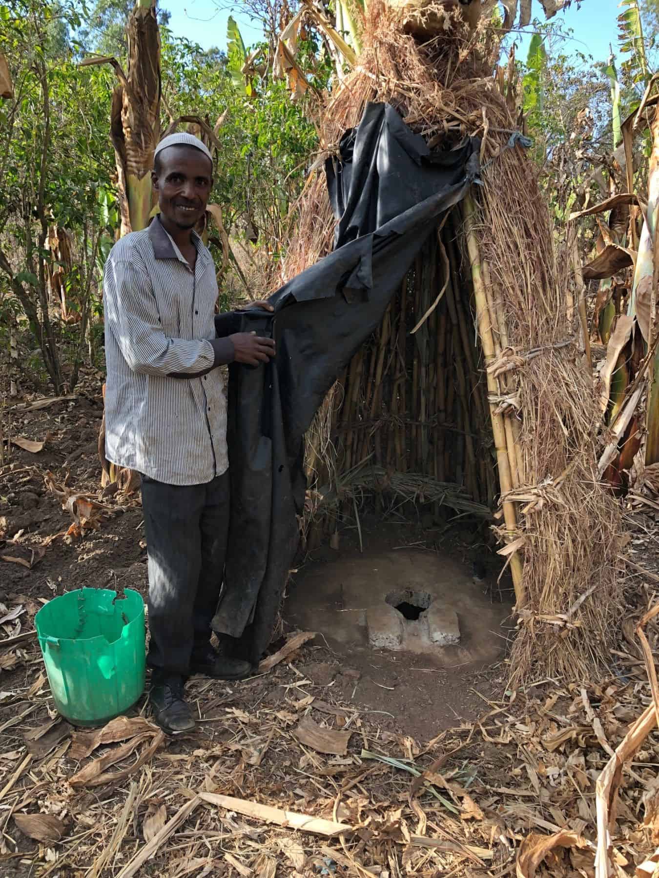 Sefa Nassir proudly showing visitors the latrine he dug and built himself, after our health and hygiene training taught him the importance of using latrines.