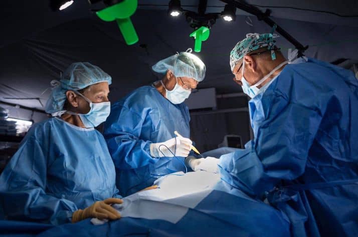 Dr. John Potts, centre, and two other surgeons operate on a patient at the field hospital.