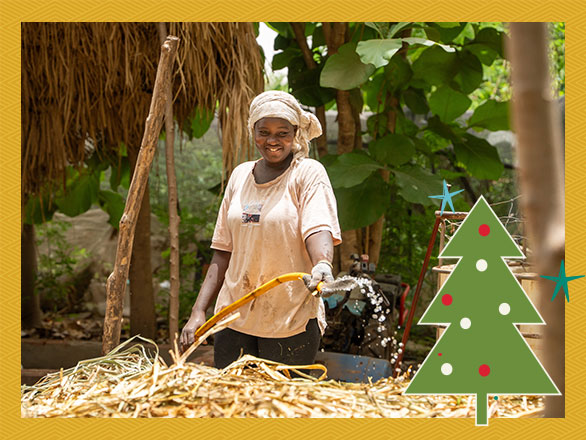 A woman smiles while operating a machine to process harvested grain, showcasing how agricultural training and tools empower individuals to create sustainable food sources.
