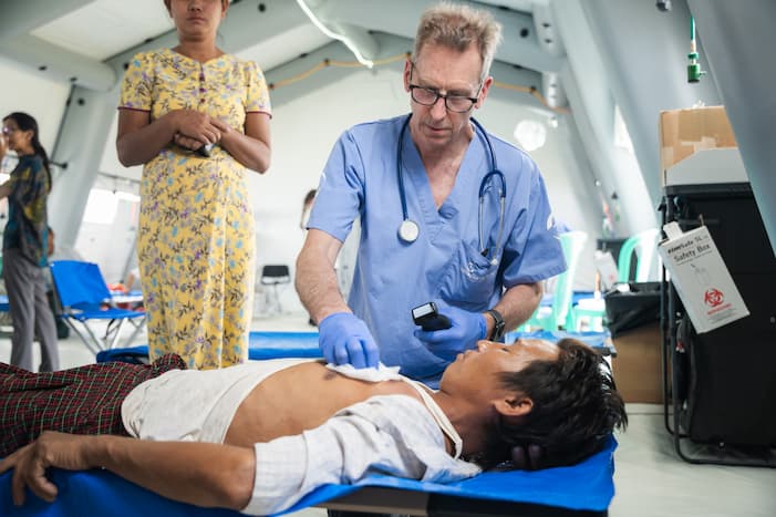 A medical professional tends to an injured man lying on a cot, demonstrating the on-the-ground, critical care provided by Samaritan's Purse teams that saves lives in the wake of disasters.