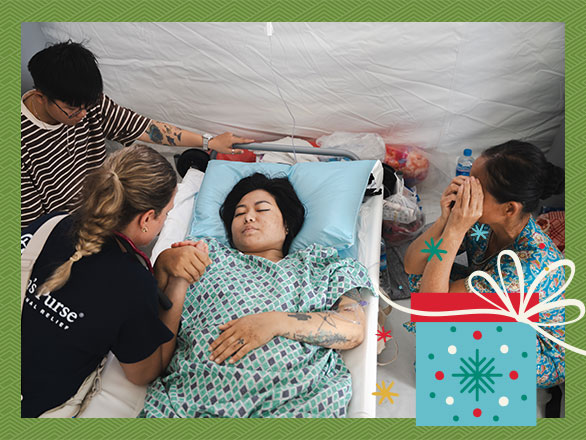 A medical team prays with Sanda and her emotional family at her bedside in the Emergency Field Hospital, showing the spiritual and emotional support she received alongside her physical healing.