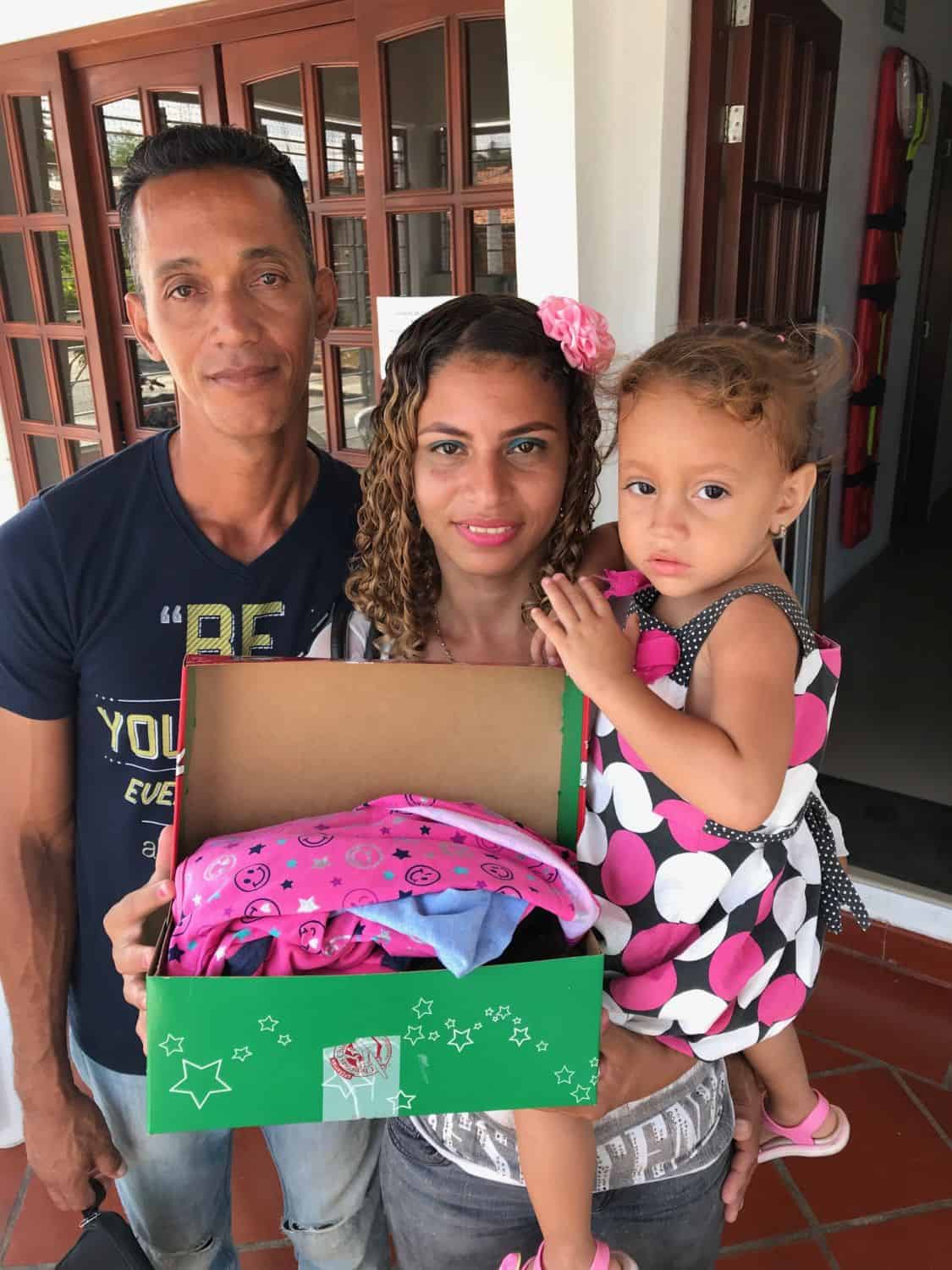 Estela with her parents, and the shoebox containing new clothes justs her size.