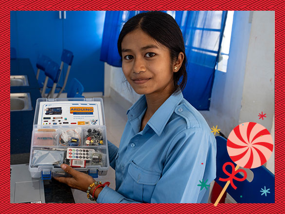 Lysa proudly holds up a STEM electronics kit in her classroom, a tool that has unlocked her passion for innovation and is helping her build a brighter future for herself and her community in Cambodia.